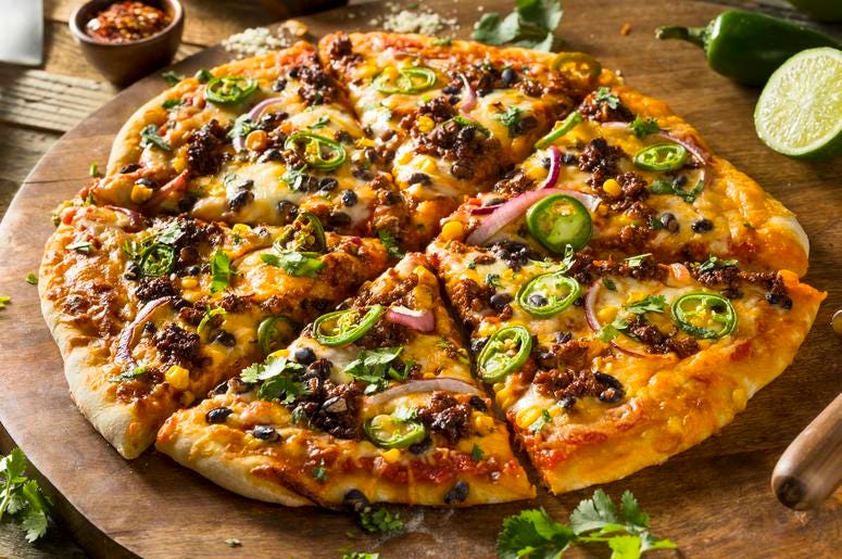 A whole pizza with sausage, olives and peppers