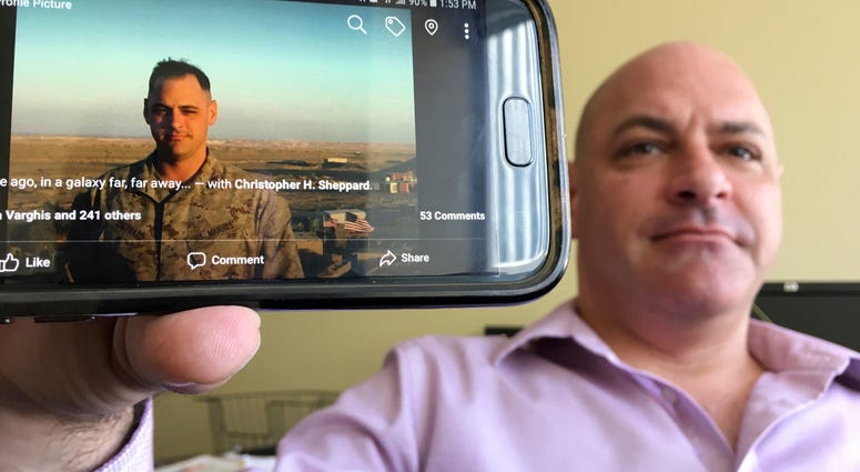 In this photograph taken July 17, 2018, Marine Corps veteran Chris Sheppard poses with a picture of himself taken during his service in Iraq in Oct. 2004, at his office in Seattle. "I thought that press conference yesterday wit