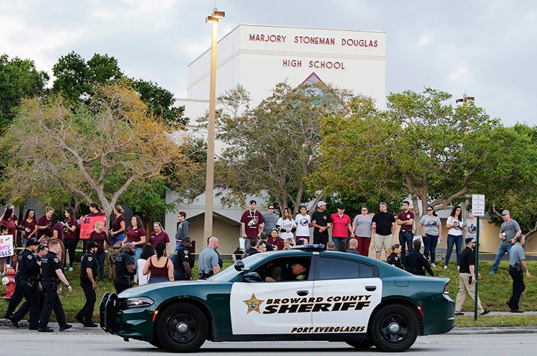 A police car drives near Marjory Stoneman Douglas High School in Parkland, Fla. Marjory_Stoneman_Douglas_Parkland_School_Shooting_Victims_Sue_School_Sheriff