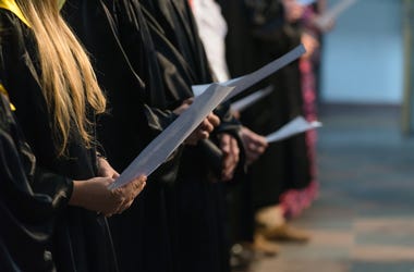 Choir singers holding musical score and singing on student graduation day in university, college diploma commencement - stock photo
