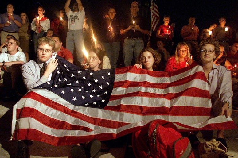 People cover themselves with an American Flag on the US Capitol grounds during a candle light vigil to remember victims who lost there life in the recent terorist attacks September 12, 2001 in Washington DC. People cover themselves with an American Flag on the US Capitol grounds during a candle light vigil to remember victims who lost there life in the recent terorist attacks September 12, 2001 in Washington DC. (Photo by Mark Wilson/Getty Images)