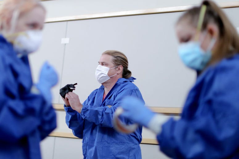 MALIBU, CALIFORNIA - APRIL 08: Volunteers (L to R) Eva Grout, Richard Garvey and Jennifer Niebergall suit up in personal protective equipment (PPE) before conducting drive-through coronavirus testing at Malibu City Hall on April 8, 2020 in Malibu, Califor
