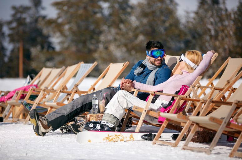 Winter holiday, ski, travel - couple relaxing together in sun at
