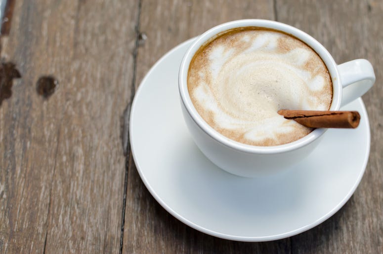 A cup of hot latte with cinnamon on wood background A cup of hot latte with cinnamon on wood background