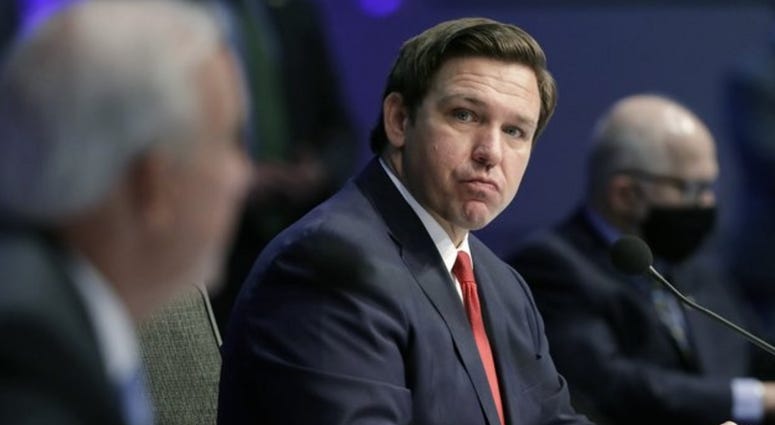 Florida Gov. Ron DeSantis, center, listens as Miami-Dade County Mayor Carlos Gimenez, left, speaks during a news conference on COVID-19, Friday, June 19, 2020
