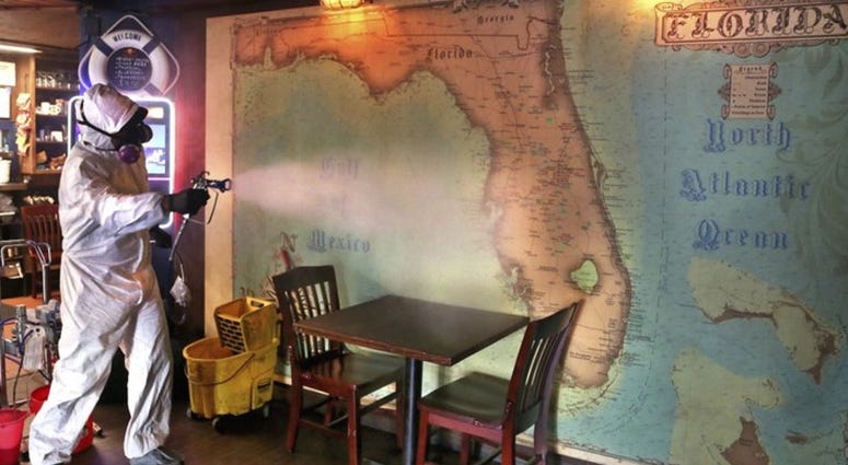 Eric Rodriguez, co-owner of Disinfectant Firm, Tampa, disinfects a map of Florida using Proxitane AHC at The Galley tavern in St. Petersburg, Fla., Wednesday, June 24, 2020.