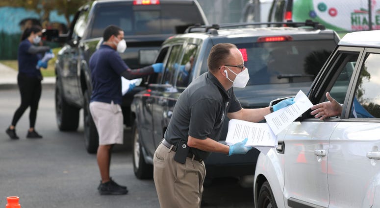 Workers hand out unemployment applications to people in their vehicles in Hialeah, Florida. The city is distributing the printed unemployment forms to residents as people continue to have issues with access to the state of Florida’s unemployment website.