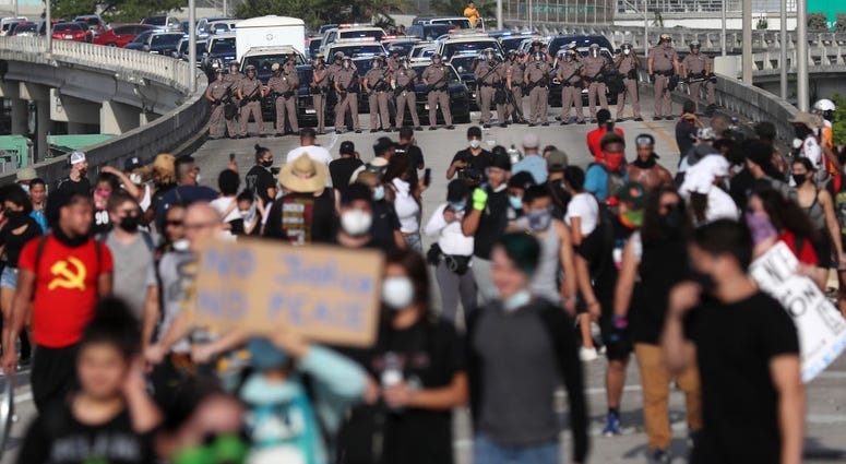 Police watch as demonstrators march onto the freeway during a protest against police brutality and the recent death of George Floyd, on May 31, 2020 in Miami, Florida.