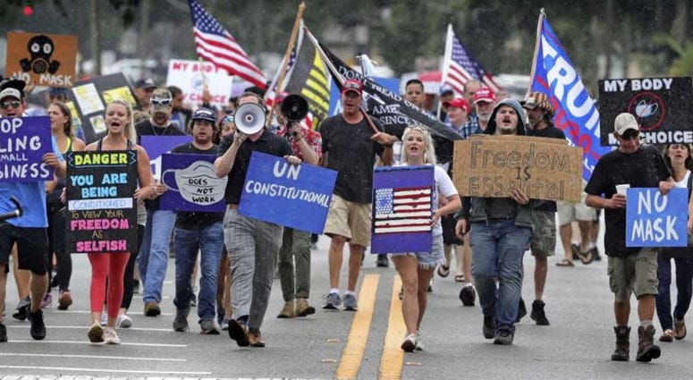 Demonstrators march through downtown Sanford, Fla., July 1, 2020, to protest a Seminole County order requiring people to wear masks in response to the spike in coronavirus cases.