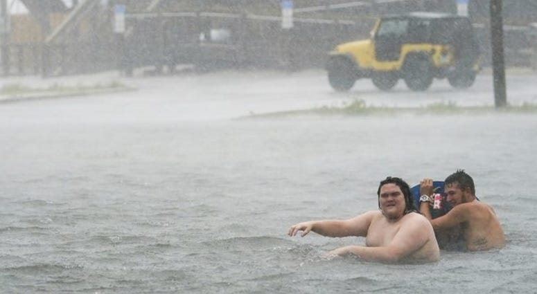 People play in a flooded parking lot at Navarre Beach, Tuesday, Sept. 15, 2020, in Pensacola Beach, Fla. Hurricane Sally is crawling toward the northern Gulf Coast at just 2 mph, a pace that's enabling the storm to gather huge amounts of water to eventual