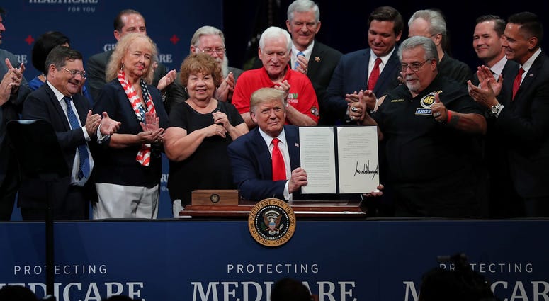 President Donald Trump sits at a table to sign an executive order concerning Medicare during an event at the Sharon L. Morse Performing Arts Center on October 03, 2019 in The Villages, Florida.