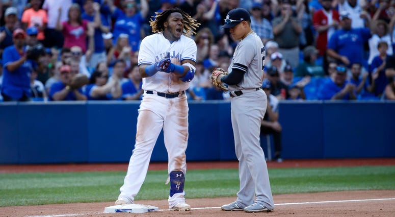 TORONTO, ON - AUGUST 10: Vladimir Guerrero Jr. #27 of the Toronto Blue Jays reacts as he is held at third base by Gio Urshela #29 of the New York Yankees after hitting a triple, allowing 2 runs in the 7th inning during MLB action against the New York Yank