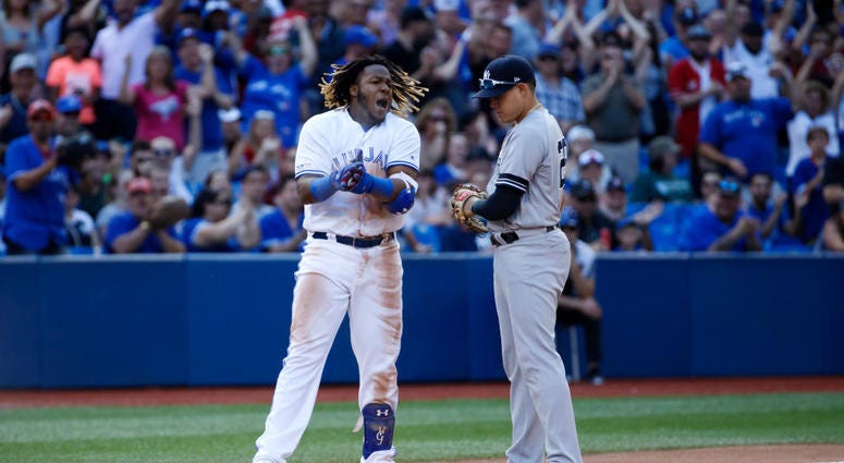 TORONTO, ON - AUGUST 10: Vladimir Guerrero Jr. #27 of the Toronto Blue Jays reacts as he is held at third base by Gio Urshela #29 of the New York Yankees after hitting a triple, allowing 2 runs in the 7th inning during MLB action against the New York Yank