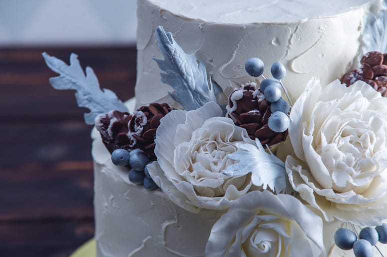 Delicate white bunk wedding cake decorated with an original design using mastic roses Delicate white bunk wedding cake decorated with an original design using mastic roses