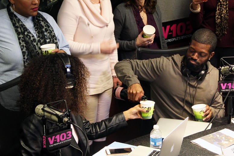 JR of The Morning Culture pouring Moet Champagne for co-host Jade Novah JR of The Morning Culture pouring Moet Champagne for co-host Jade Novah