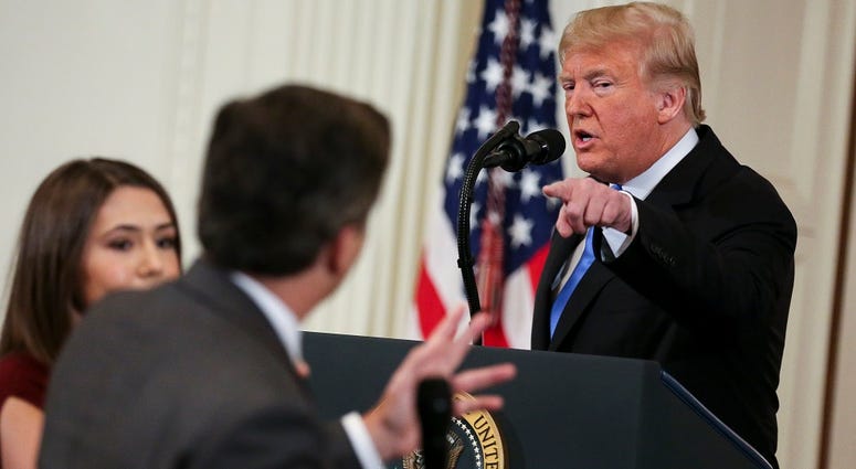 A White House staff member, left, tries to take away the microphone from CNN White House correspondent, Jim Acosta, during an exchange with President Donald Trump after giving remarks a day after the midterm elections on November 7, 2018 in Washington, DC