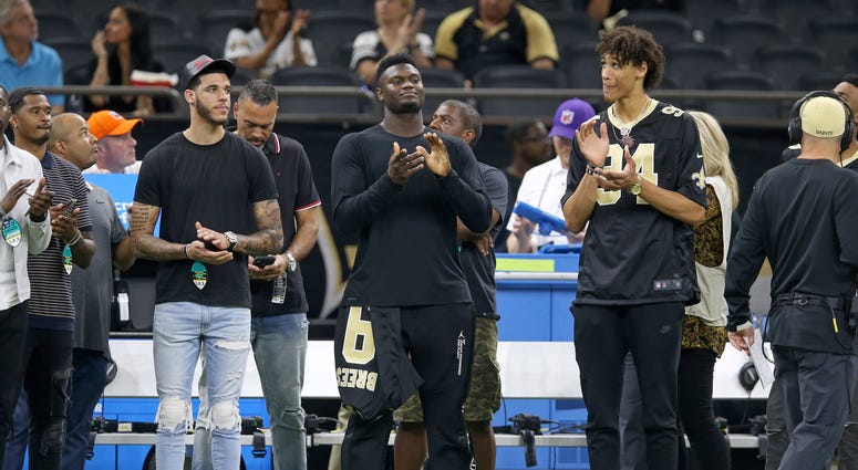 New Orleans Pelicans players Lonzo Ball (left) and Zion Williamson (center) and Jaxson Hayes (right) look on from the sidelines before the game between the New Orleans Saints and the Houston Texans at the Mercedes-Benz Superdome.