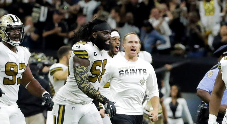 New Orleans Saints outside linebacker Demario Davis (56) and quarterback Drew Brees (center) celebrate after a 12-10 win against the Dallas Cowboys at the Mercedes-Benz Superdome.