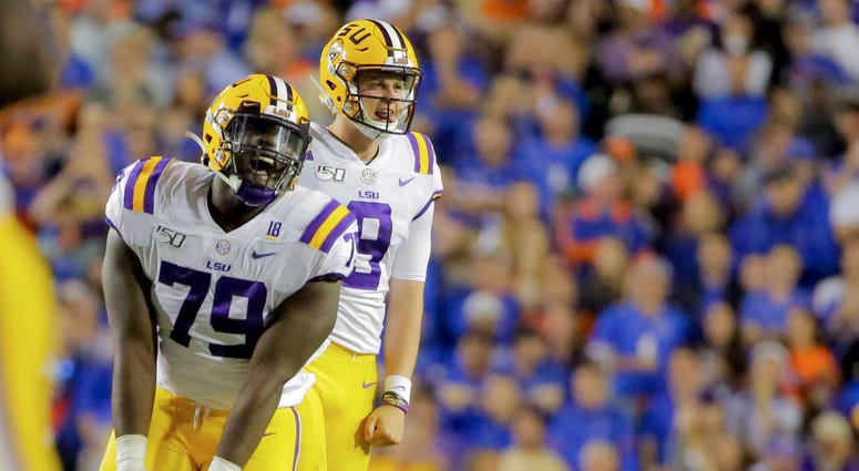 LSU Tigers quarterback Joe Burrow (9) and center Lloyd Cushenberry III (79) celebrate after a touchdown against the Florida Gators during the fourth quarter at Tiger Stadium.