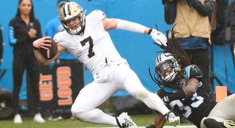 New Orleans Saints quarterback Taysom Hill (7) scores a touchdown as Carolina Panthers free safety Tre Boston (33) defends in the third quarter at Bank of America Stadium.