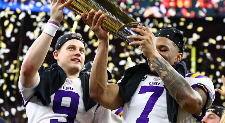 LSU Tigers safety Grant Delpit (7) hoists the national championship trophy with quarterback Joe Burrow (9) after a victory against the Clemson Tigers in the College Football Playoff national championship game at Mercedes-Benz Superdome.