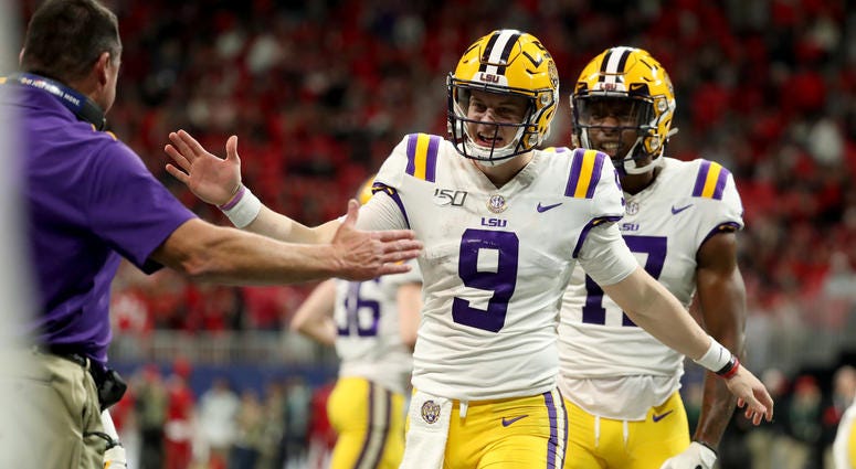 LSU Tigers quarterback Joe Burrow (9) celebrates his fourth passing touchdown with head coach Ed Orgeron in the third quarter against Georgia Bulldogs in the 2019 SEC Championship Game at Mercedes-Benz Stadium.