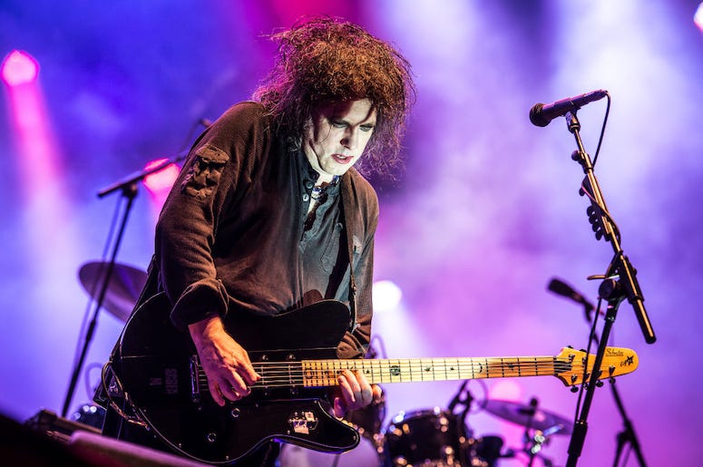 Robert Smith of The Cure plays guitar during a concert.