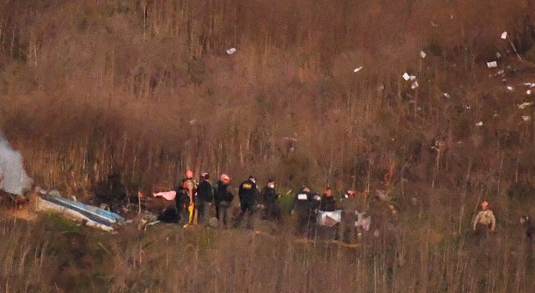 A body is carried from the scene of a helicopter crash that killed former NBA basketball player Kobe Bryant