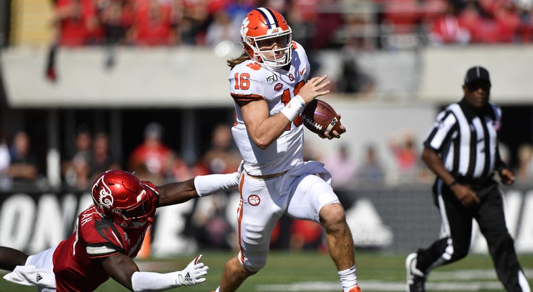 Clemson Tigers quarterback Trevor Lawrence (16) runs the ball against Louisville Cardinals linebacker Yasir Abdullah (22) during the second half of play at Cardinal Stadium.
