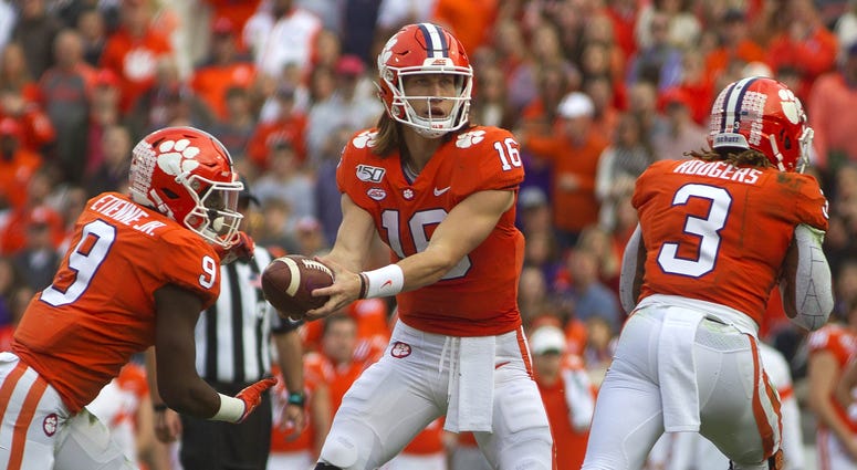 Clemson Tigers quarterback Trevor Lawrence (16) hands the ball off to running back Travis Etienne (9) against the Wake Forest Demon Deacons during the first quarter at Clemson Memorial Stadium.