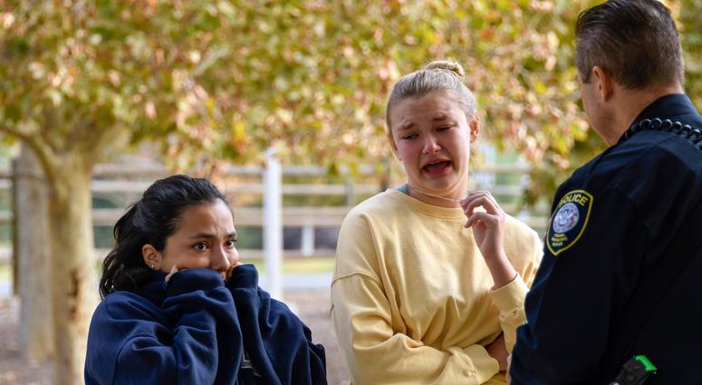 Two Saugus High students talk to a police officer at a reunification point after a shooting at Saugus high school in Santa Clarita, California. Family members were reunited with students at Grand Park located near the school.